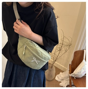 Close-up of green crossbody bag with white bow embroidery on lightweight nylon fabric