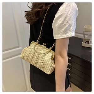 Détail du sac coquillage en paille tressée avec fermoir vintage et bandoulière en chaîne dorée