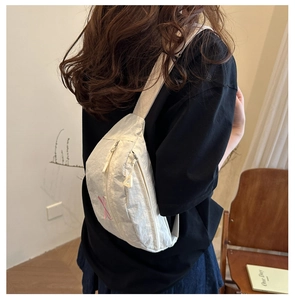 Close-up of white crossbody bag featuring pink embroidered details and nylon fabric