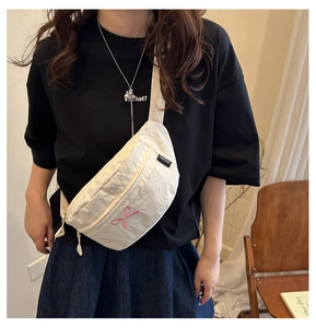 Detail of off-white nylon belt bag worn by model featuring pink butterfly embroidery