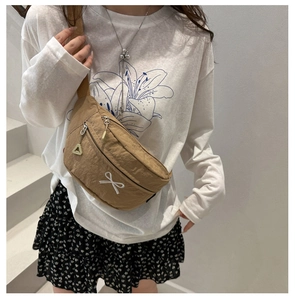 Close-up of beige nylon crossbody bag with white bow embroidery and adjustable strap