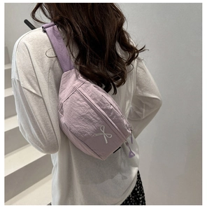 Detail of light purple nylon crossbody bag featuring white bow embroidery and strap
