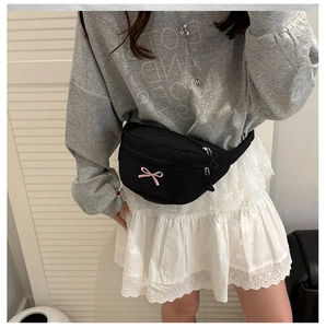 Detail of black nylon chest bag featuring pink bow embroidery and silver zipper
