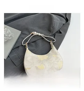 Detailed view of half-moon hobo bag featuring yellow floral prints and gold hardware