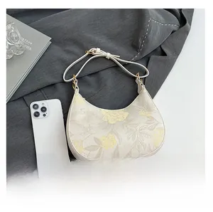 Detailed view of crescent floral bag with gold hardware on a stylish office setting