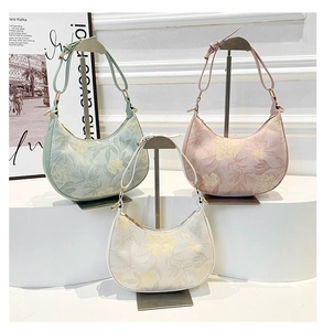 Detailed view of floral print hobo bags in green, pink, and beige on display stands