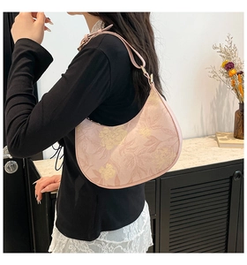 Pink floral hobo bag with adjustable strap worn by a model in a minimalist setting