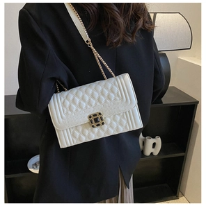 Detail of white quilted crossbody bag with gold chain strap and square buckle on model