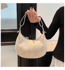 Detail of floral hobo bag featuring adjustable leather strap and golden metal buckle