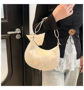 Detail of hobo shoulder bag featuring elegant yellow floral print and gold hardware