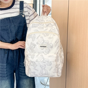 Gros plan d'un sac à dos blanc en toile avec motifs d'ours et détails de la poche avant