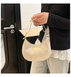 Detailed view of white half-moon hobo bag with floral prints and gold hardware detail