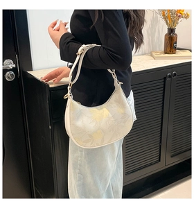 White hobo shoulder bag with floral print and gold buckle shown on a model