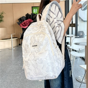 Vue latérale d'un sac à dos blanc avec imprimés d'ours porté par un mannequin au café