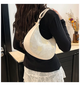 Detail of floral crescent shoulder bag showing premium stitching and gold hardware