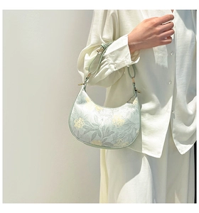 Detail view of floral green dumpling bag with metal hardware and thin shoulder strap