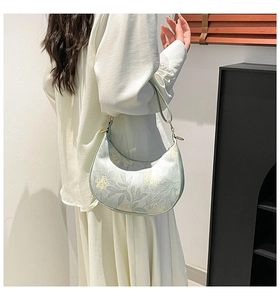 Detailed look at the floral pattern and gold hardware on the light green crescent bag