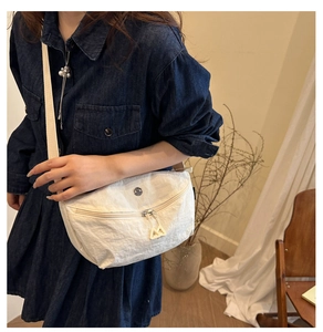 Detail of white nylon crescent bag showing textured fabric and double zipper pullers
