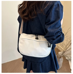 Detailed view of a white crescent moon shoulder bag paired with a denim dress outfit