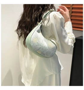 Detail of light green leather and vintage floral jacquard pattern on a hobo bag