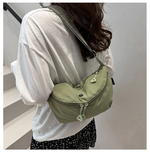 Close-up of green nylon crescent bag with silver zipper and wide gray shoulder strap