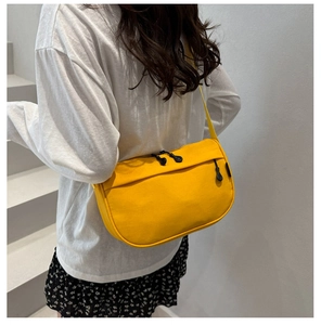 Close-up of bright yellow nylon crossbody bag featuring black zippers and top handle