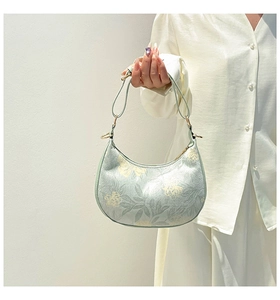 Detail of light green floral half-moon handbag with premium faux leather texture