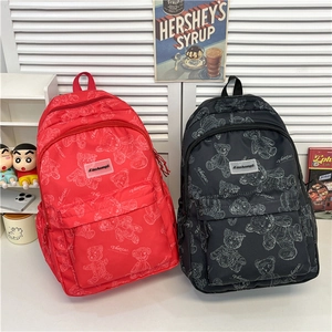 Détail des sacs à dos en nylon rouge et noir avec motifs d'ours et logos