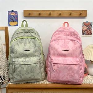 Détail de grands sacs à dos scolaire rose et vert avec motifs ours et poches zippées
