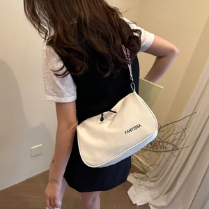 Minimalist white underarm bag with tricolor striped strap shown on a model
