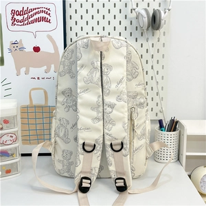 Détail du sac à dos en toile beige avec motifs d'ours en peluche gris et poche latérale