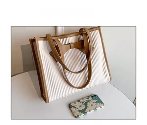 Detailed comparison showing size of white pleated tote bag with brown leather bow and strap