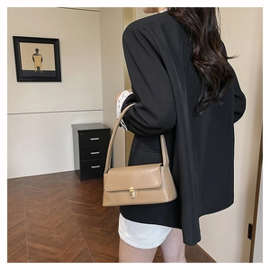 Close-up of minimalist khaki leather bag featuring a retro golden metal buckle and wide strap