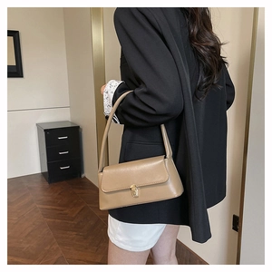 Détail du sac baguette kaki avec boucle en métal doré et bandoulière sur l'épaule