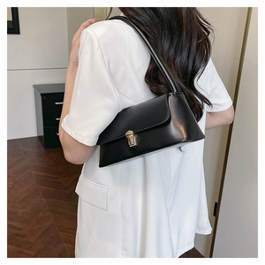 Detail of minimalist black matte leather underarm bag with gold metal buckle closure