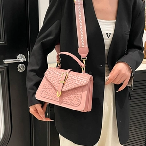 Pink woven leather crossbody bag with V-shaped metal buckle and floral strap on model