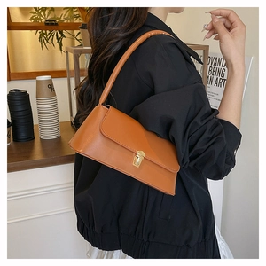 Detailed side view of caramel faux leather shoulder bag with gold metal clasp on a model