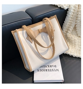 Detail of white pleated tote bag with khaki leather trim and centered bow accent
