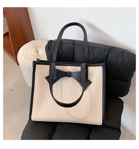 Detailed view of large black bow on white pleated tote bag with high-capacity design