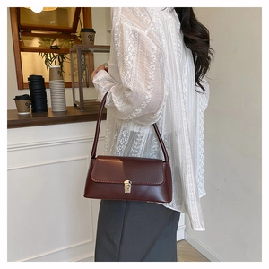 Detail of deep red shoulder bag with gold square buckle shown from a side-rear perspective