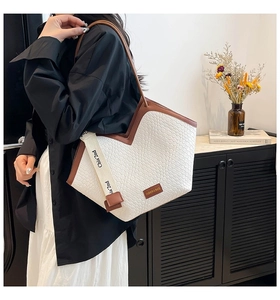 Close-up of woven texture and brown leather trim on a stylish large capacity tote bag