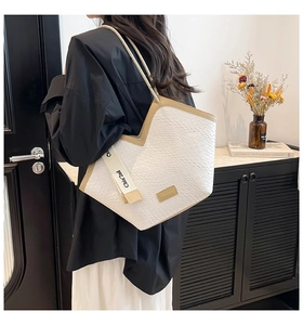 Detailed side view of a white woven tote bag with contrasting beige leather edges and trim