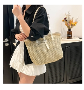 Vue latérale d'un sac cabas tissé beige avec des anses en cuir blanc porté par un mannequin
