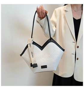 Detail of white woven tote bag with V-shaped leather trim and branding logo