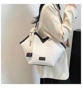 Detail of white woven tote bag with V-shaped opening and black leather piping edges