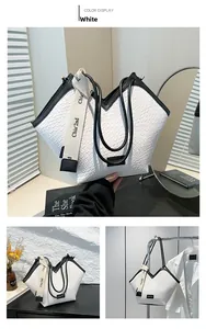Detail of white woven tote bag featuring a V-shaped top and black leather handles
