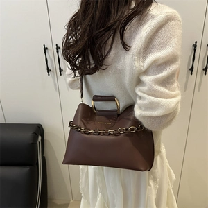 Minimalist brown leather tote bag with semi-circular gold metal handle and chain strap