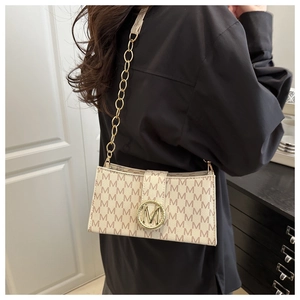 Detail of beige rectangular underarm bag with M-pattern print and gold logo magnetic buckle