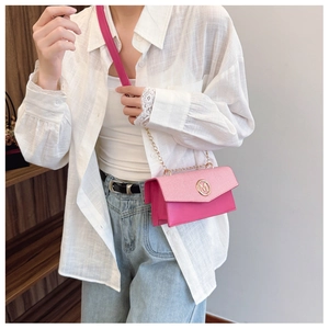 Detalle del bolso bandolera rosa con tapa tejida y hebilla metálica dorada en forma de M