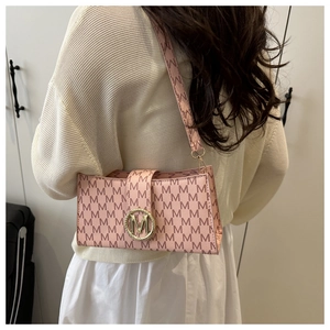 Pink shoulder bag with 'M' pattern and gold logo clasp, shown worn on a model